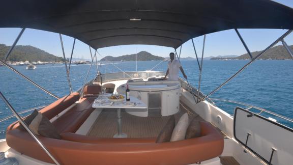 Luxuriöser Entspannungsbereich auf der Motoryacht Act mit Getränken auf dem Tisch und herrlichem Meerblick.